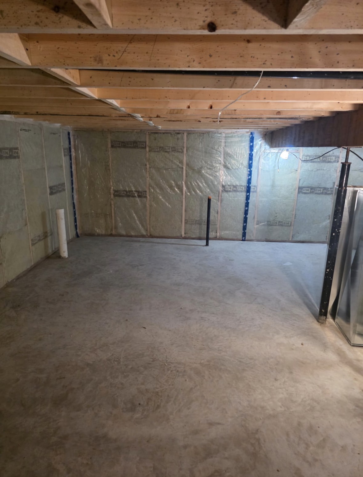 Basement before ductwork installation, with exposed ceiling joists and an open floor area