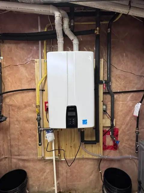 Wall-mounted Navien tankless water heater with connected piping and overhead vents